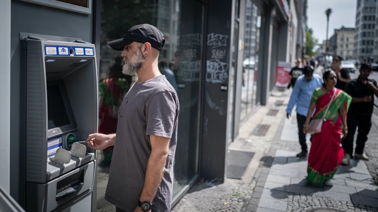 Man inserting his bank card into an ATM on the street