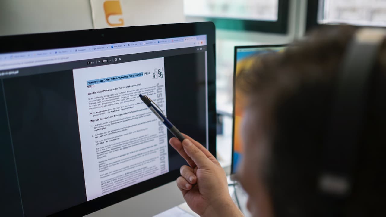 Person pointing to a leaflet about legal aid on a screen