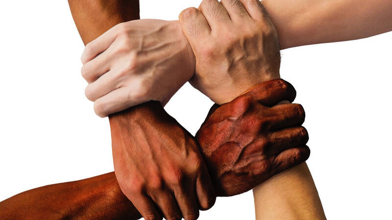 Four arms with different skin tones grabbing each other